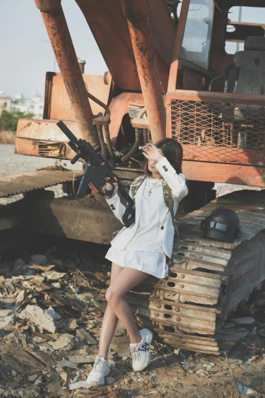 a woman holding a machine gun while standing next to a construction site