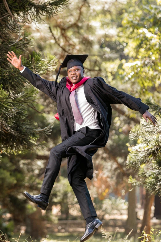 a guy in graduation gown jumping up in the air