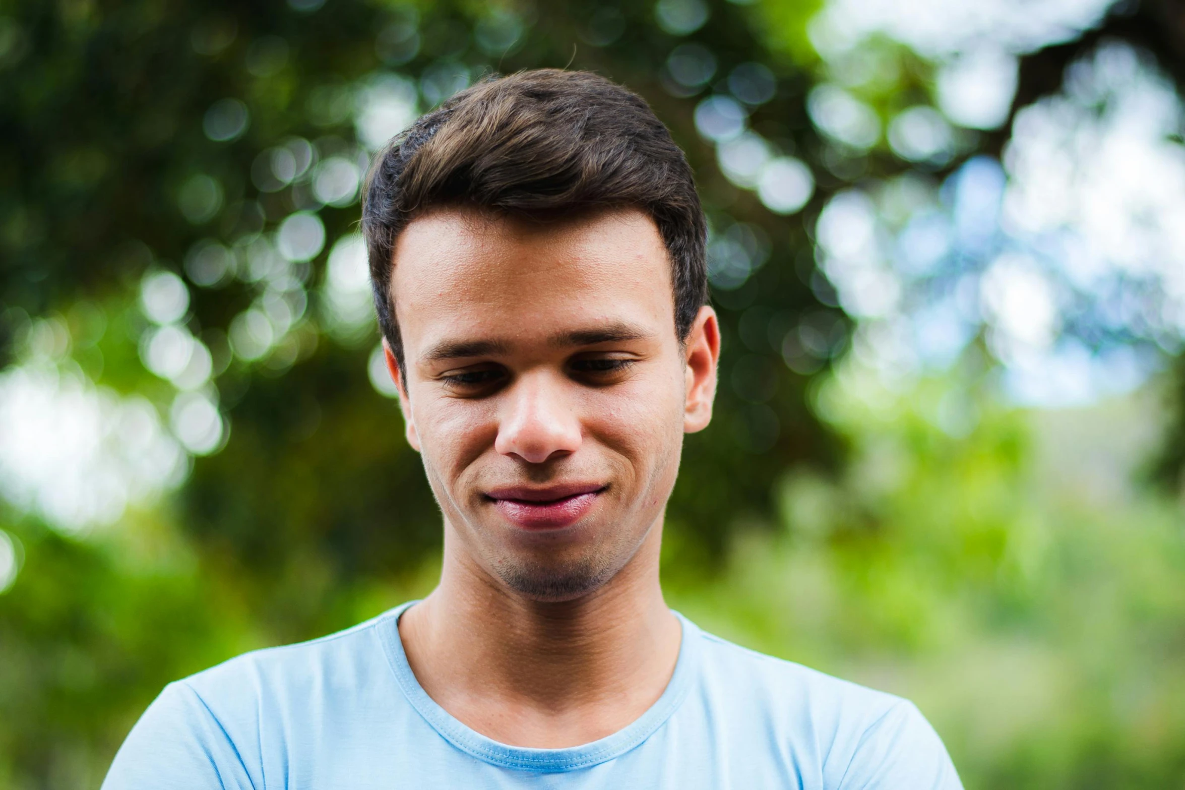 a young man wearing a blue shirt is looking at his cell phone