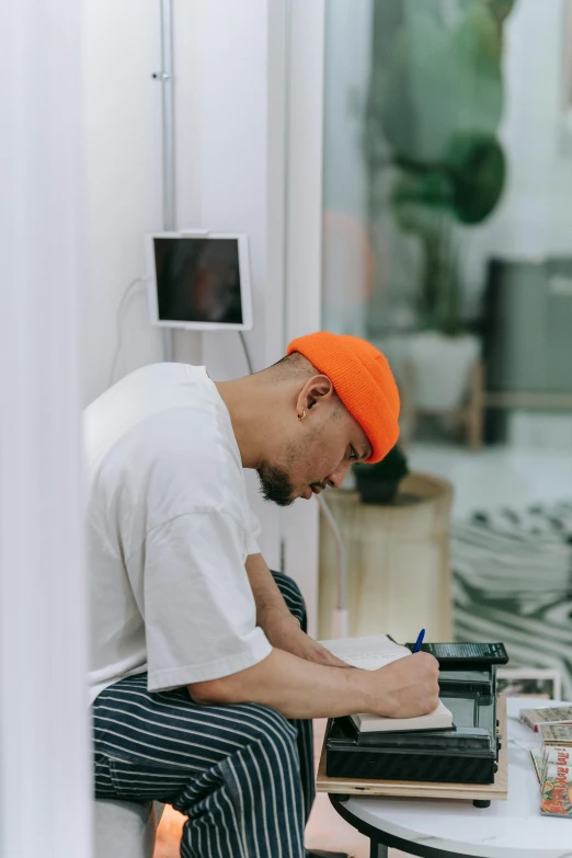 the man is sitting down writing on a notebook