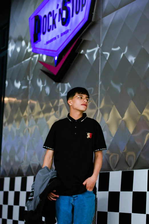 the boy is standing in front of the neon rock and stop sign