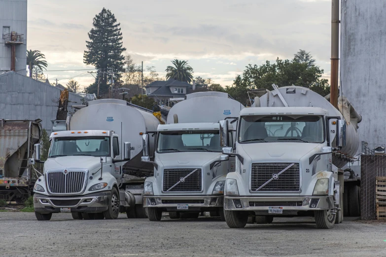 three big rig trucks parked outside a grain plant