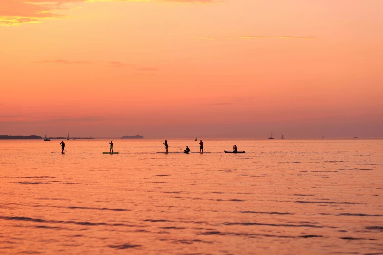 some people surfing on a calm body of water