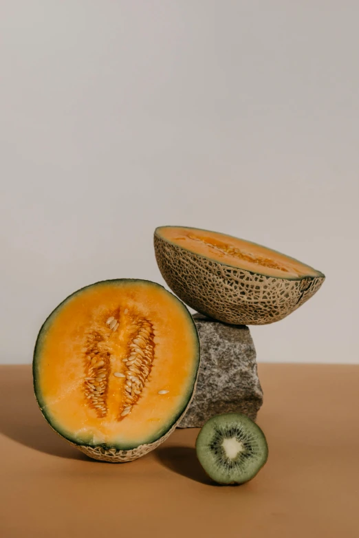 a whole melon next to some sliced kiwi