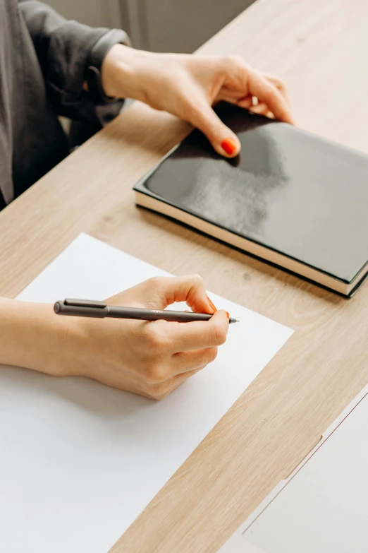 a woman is holding a pen on a paper with a notepad