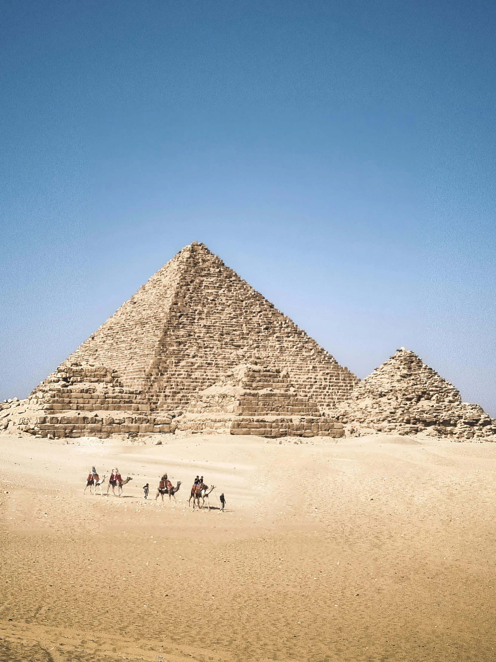 people on camels in front of the great pyramid