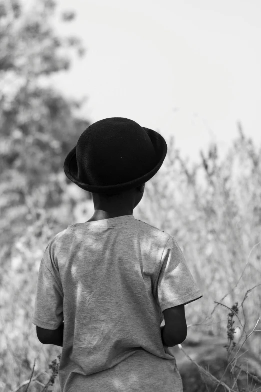 a child is sitting in the bushes wearing a hat