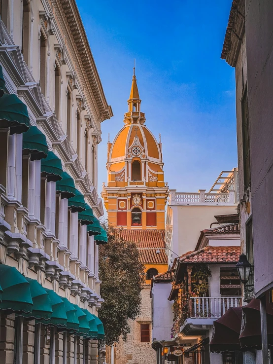 a yellow and brown clock tower stands high above some buildings