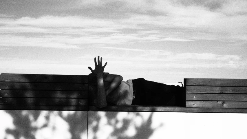 hands reaching up out from a bench with the shadow of two people on it