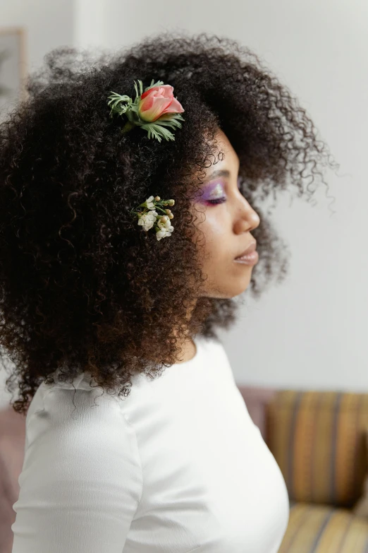 a woman with dark skin and curly hair wearing a flower in her hair