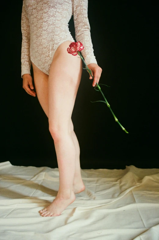 a woman's bare - leg holds flowers over her skin