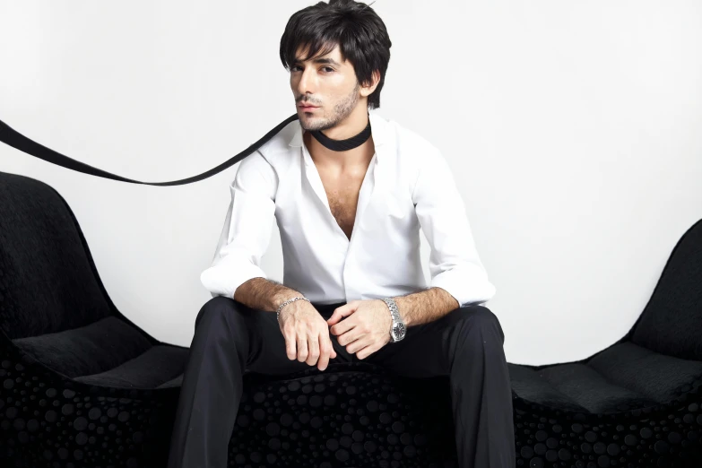 a man sits on a black chair with a white shirt on