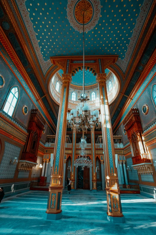 a large blue and gold room with high ceiling and chandeliers