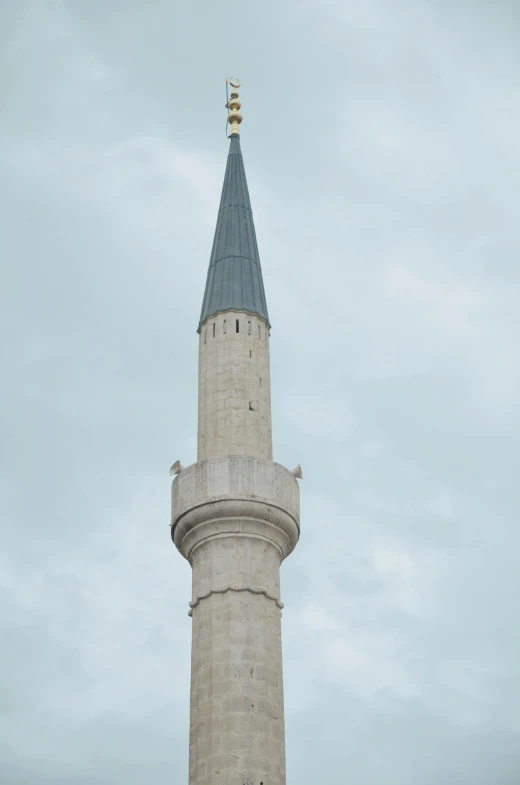 a very tall grey tower with a weather vein on it's top