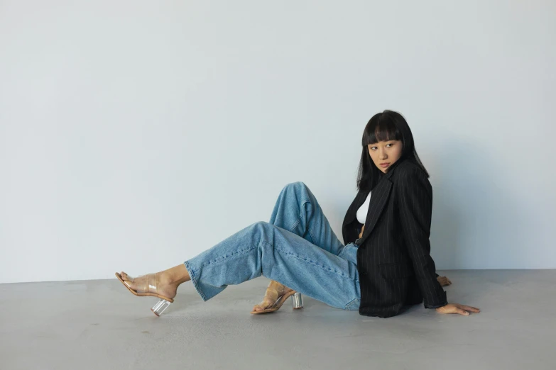 a woman in black coat and jeans sitting on the floor
