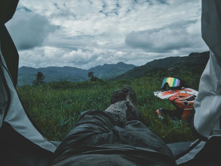 a man is sleeping in the grass with an open tent