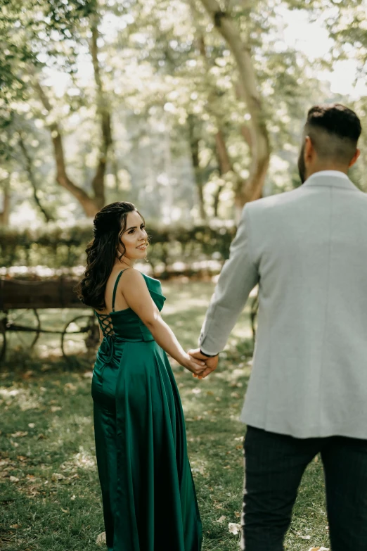 a young man and woman holding hands in the woods