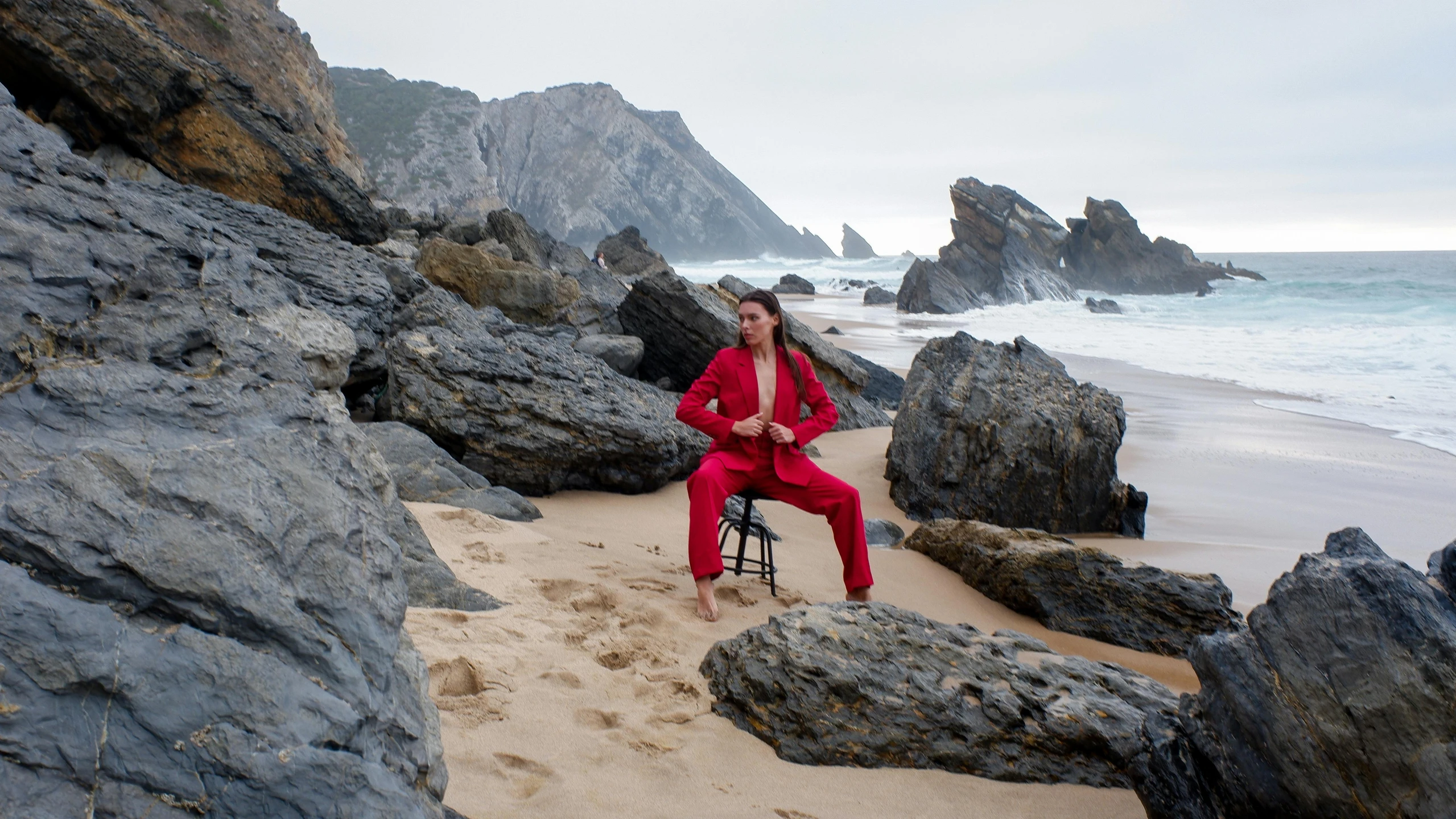 a woman sitting on top of a chair in front of the ocean