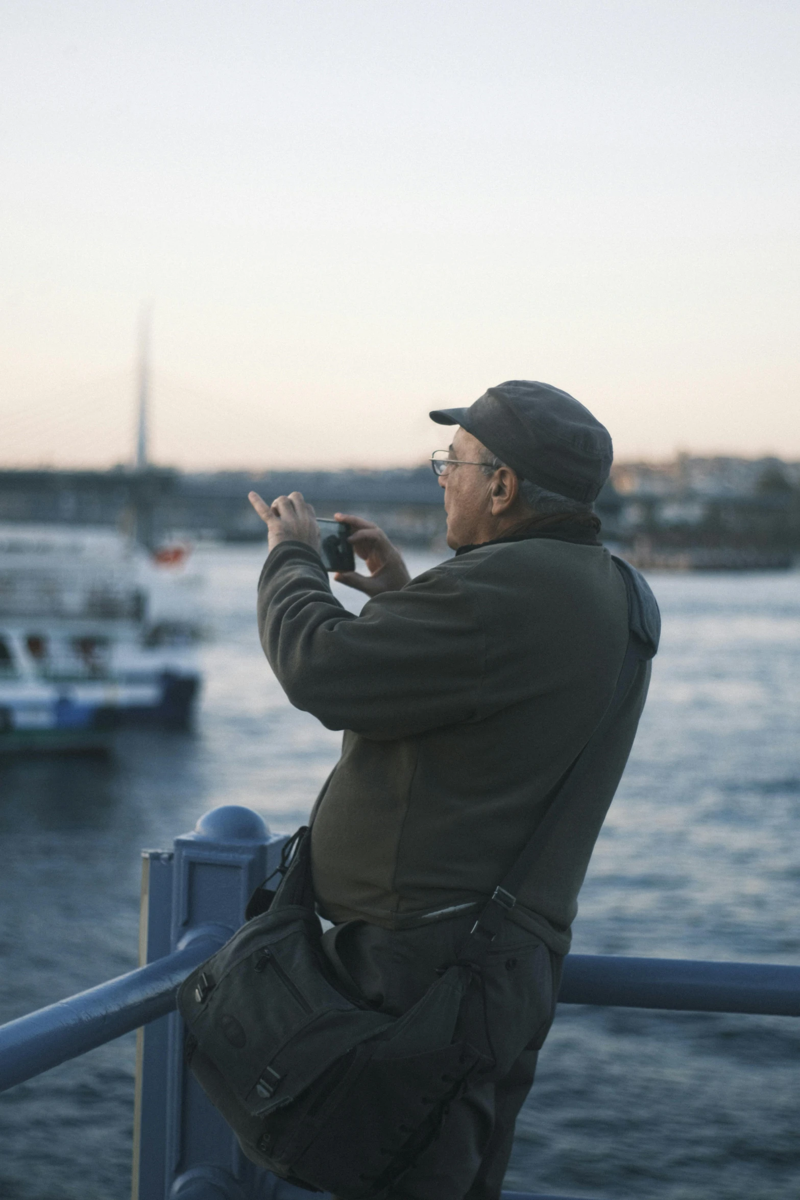 a man in a hat and glasses stands with his hands behind his back