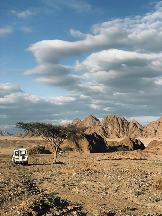 a car is parked by some mountains under a blue sky