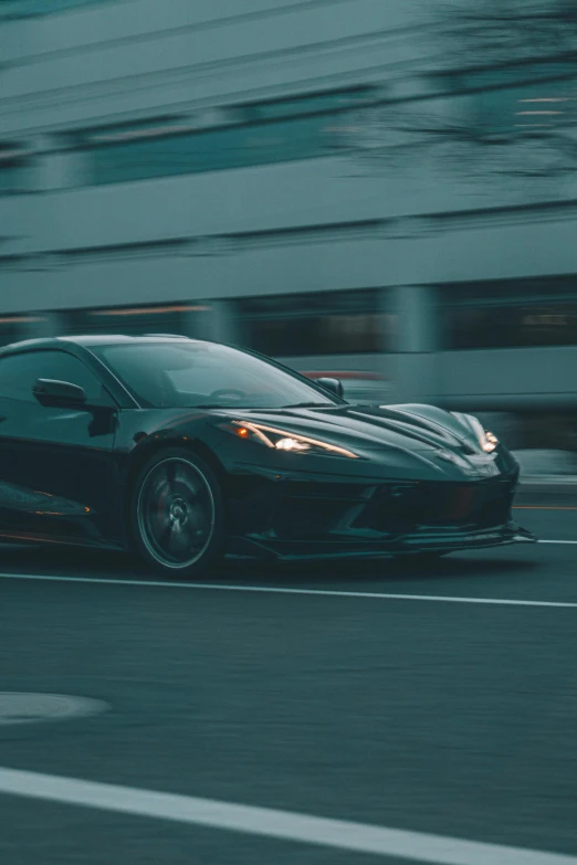 a sports car driving on a city road in front of a building