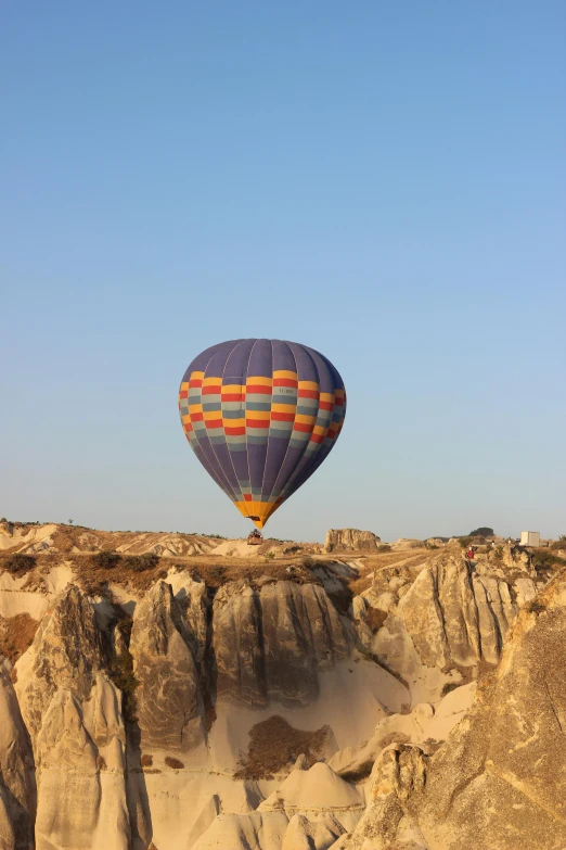 two  air balloons flying in the sky over a rocky outcrop