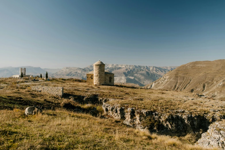 a small stone structure with hills in the background