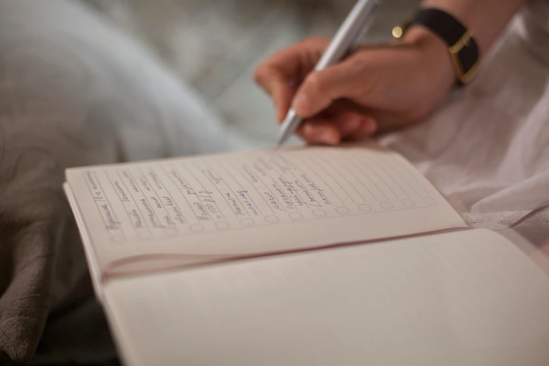 a person with a pen in their hand writing on a white paper