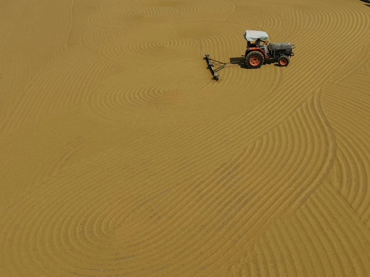 there is a mower going through the sand