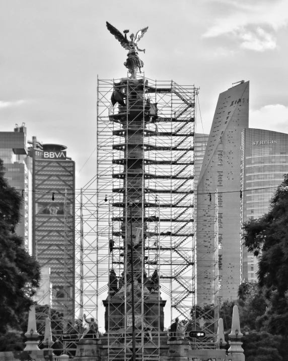 a statue with a scaffold on it in front of a city