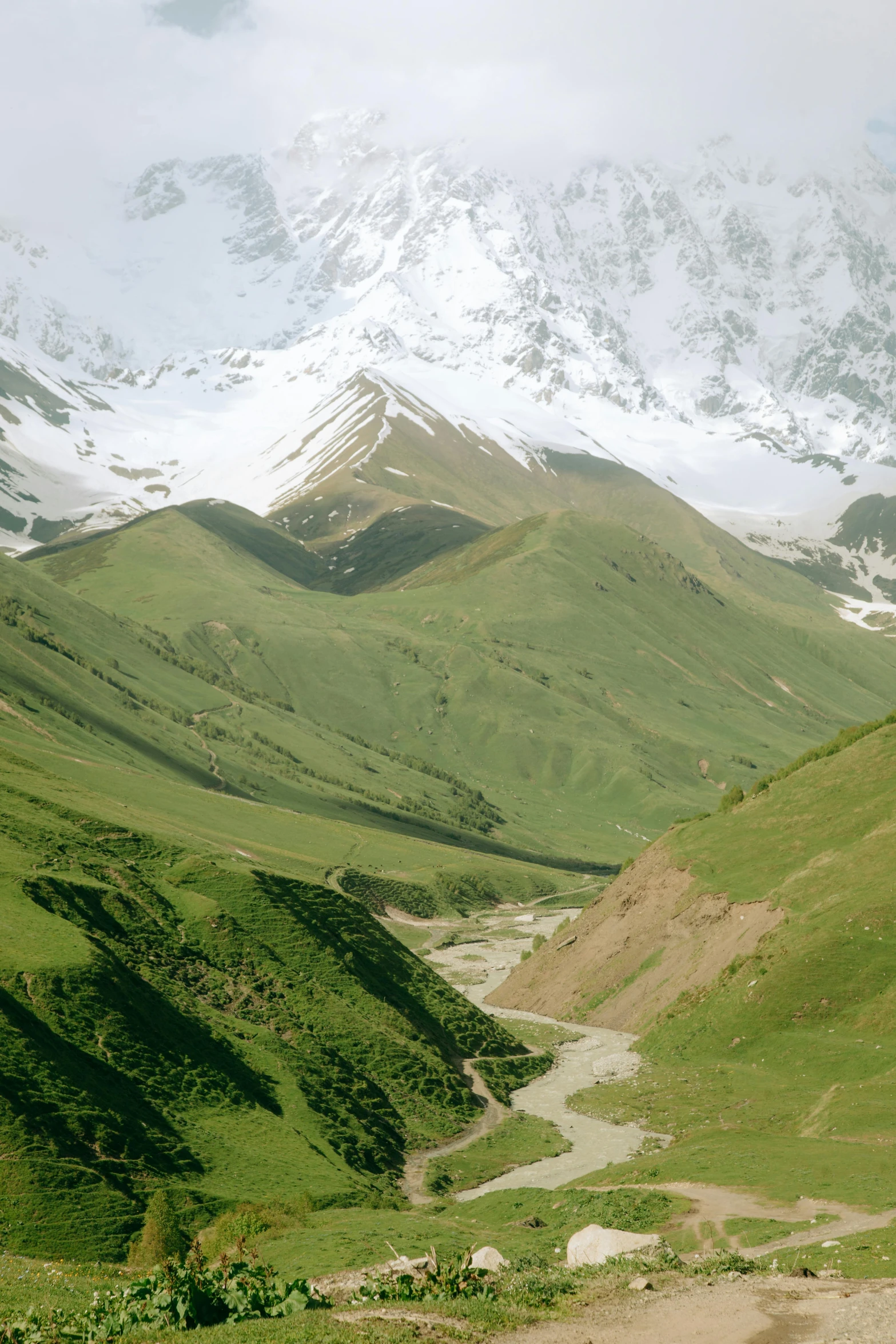 a very tall snow covered mountain with a river below it