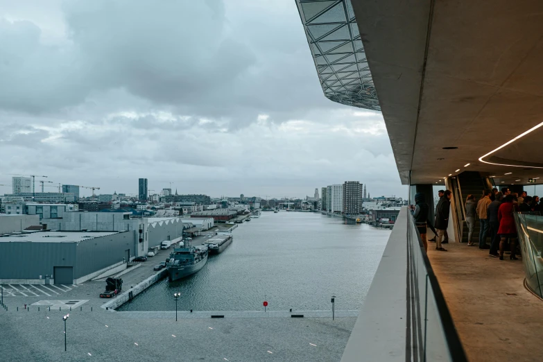 several people are standing on a balcony overlooking the water