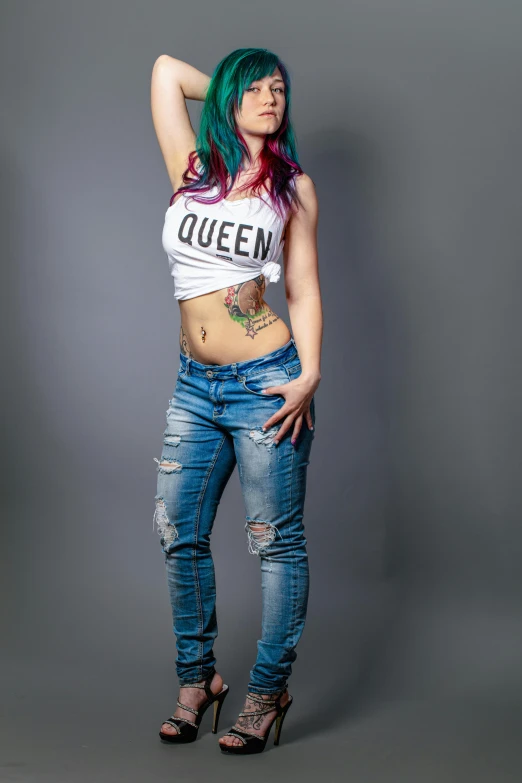 a woman with long blue hair and tattoos standing in jeans