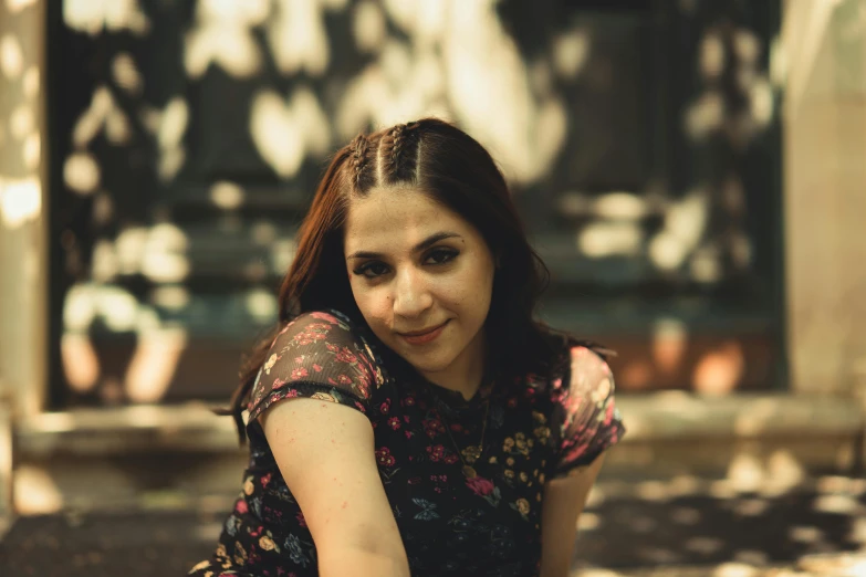 a woman is posing on the ground by a tree