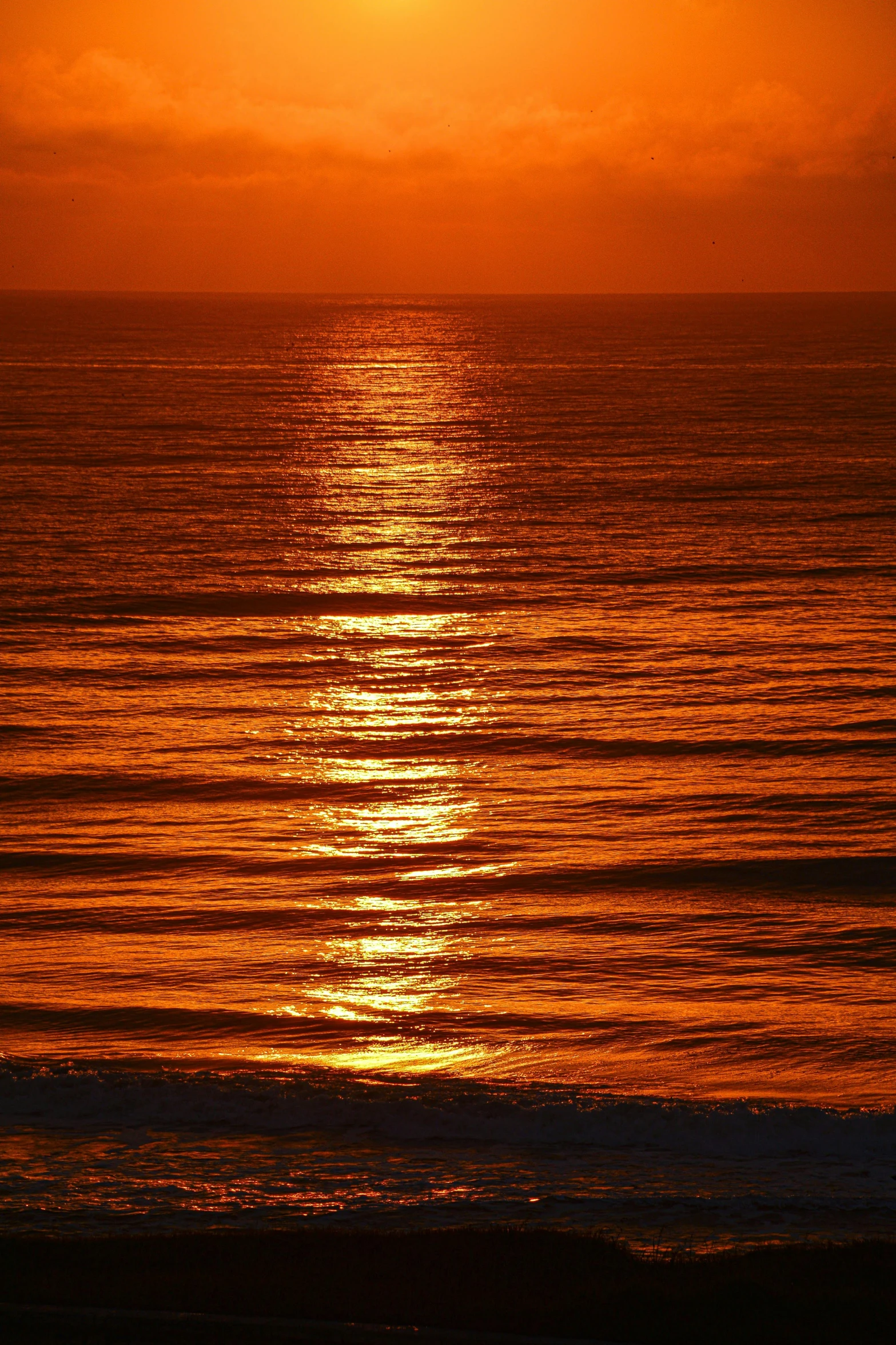 a man walking on a beach at sunrise