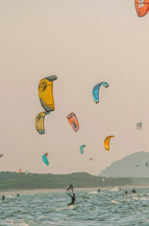 people flying kits over the ocean in front of mountains