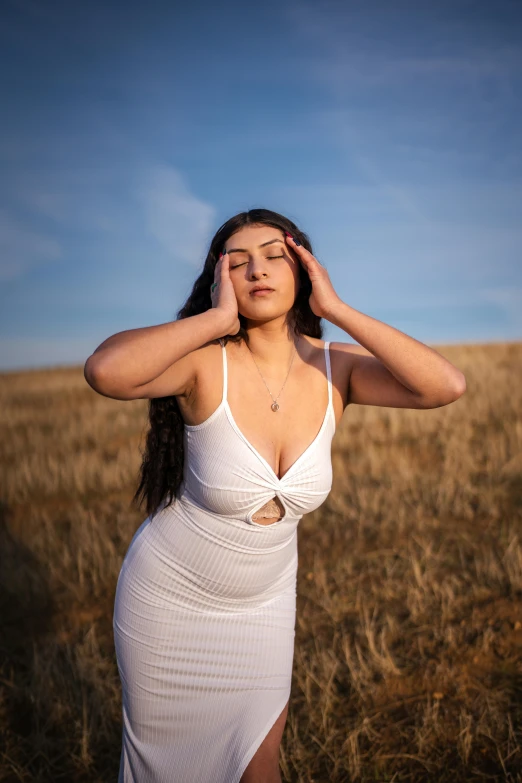 a woman is standing in a field with her eyes closed