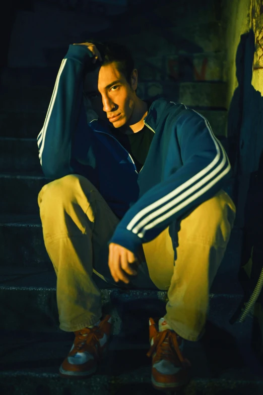 the man is sitting on steps wearing a tennis jacket