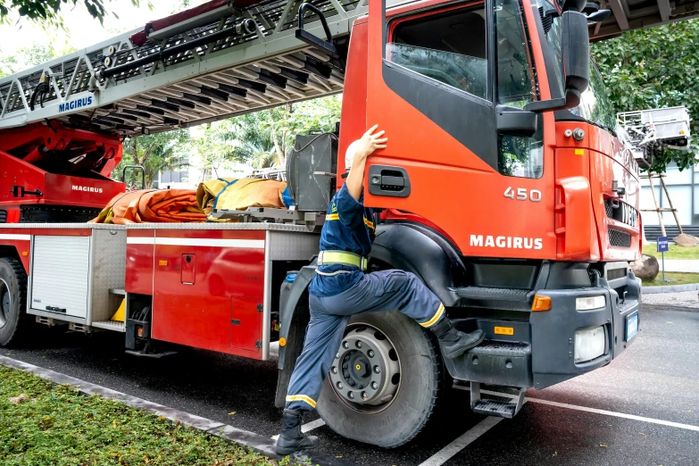 a man with a large orange truck next to trees