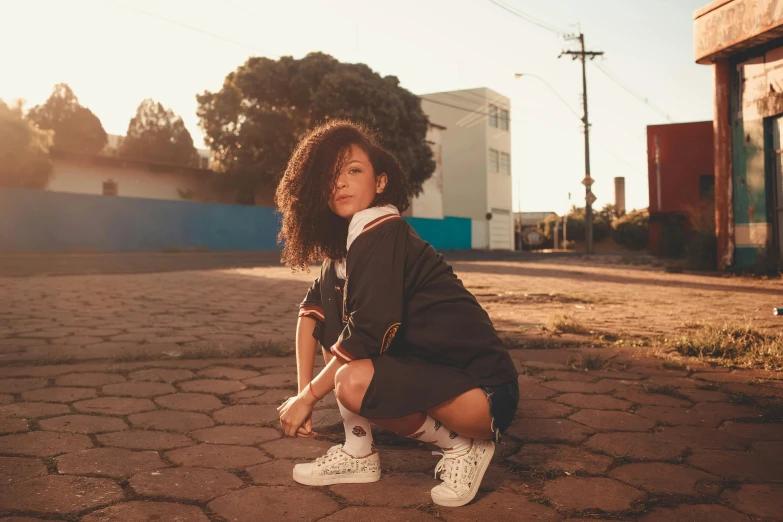 a young woman crouching down, leaning forward in a brick courtyard