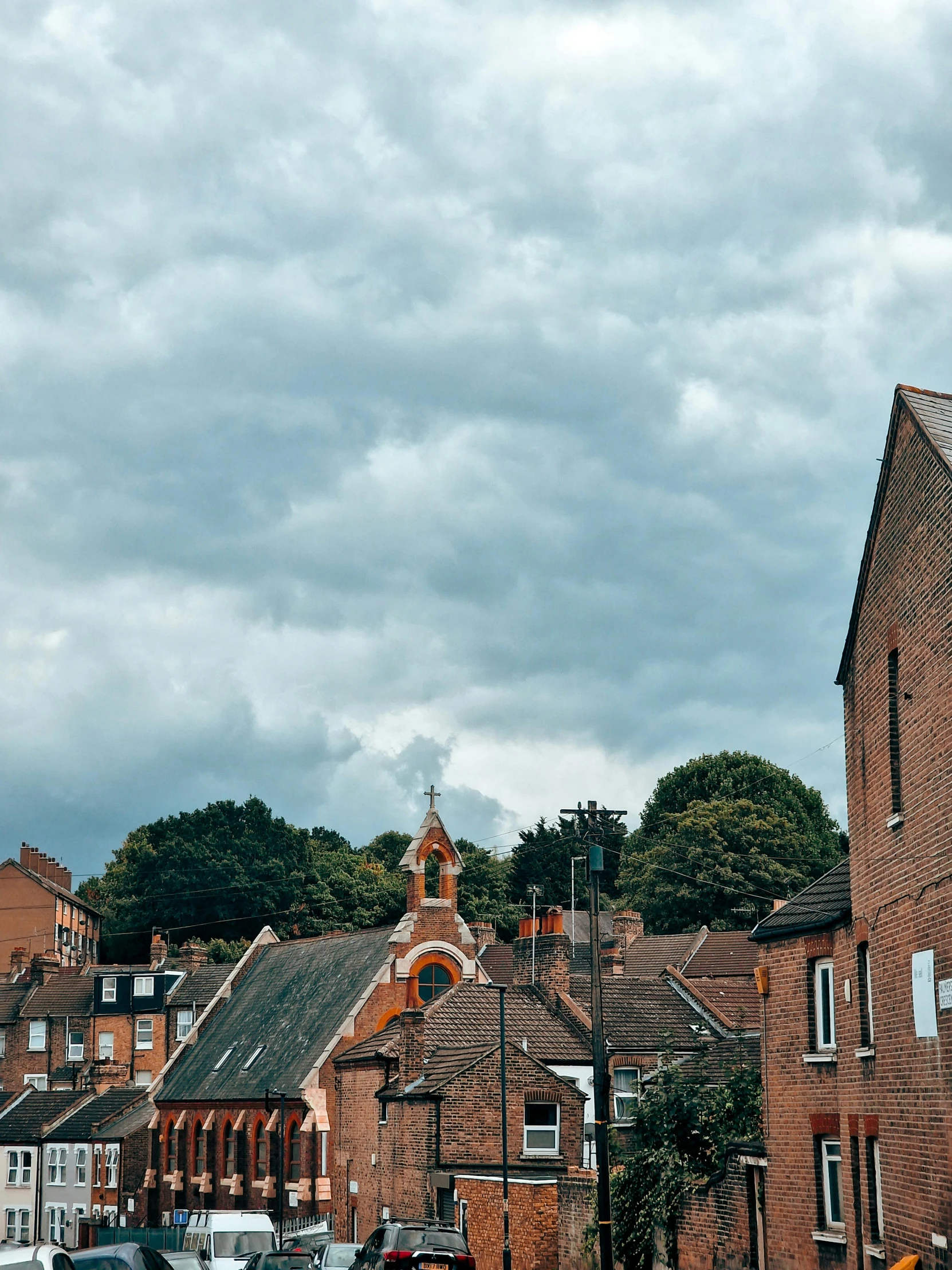 a city street with parked cars and brick buildings