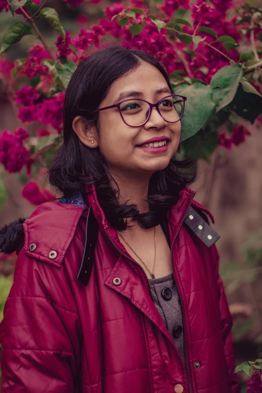 a woman wearing glasses standing by a tree