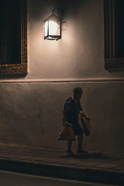 a person in the street near a building with a lamp