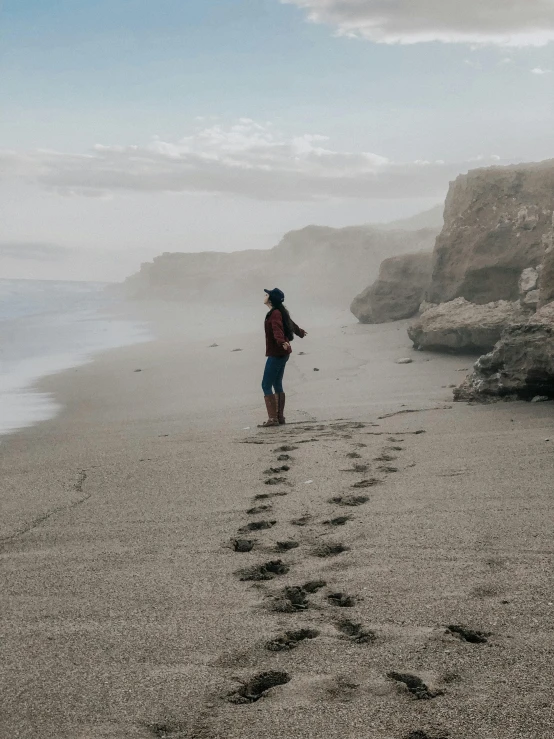 a man standing on the beach next to footprints