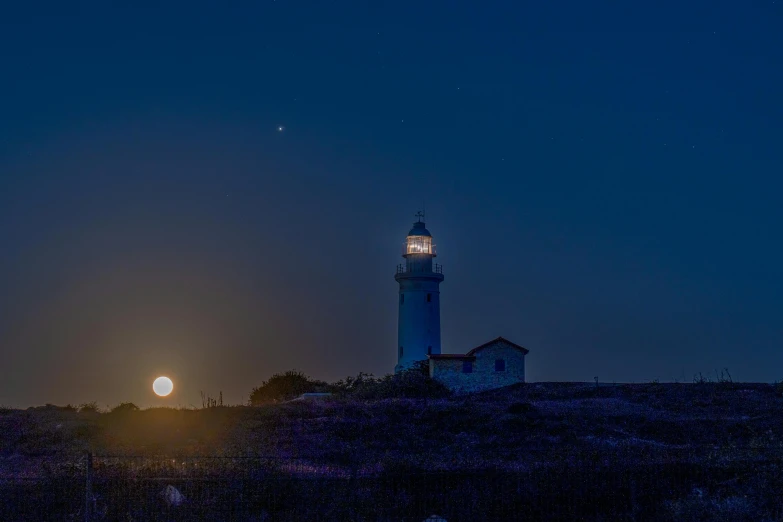 a view of a light tower with the moon setting in the background