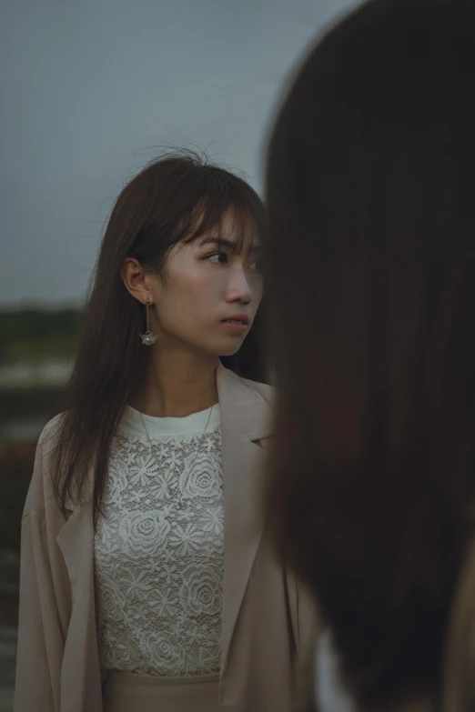 a woman in an overcoat stands and looks at her friend