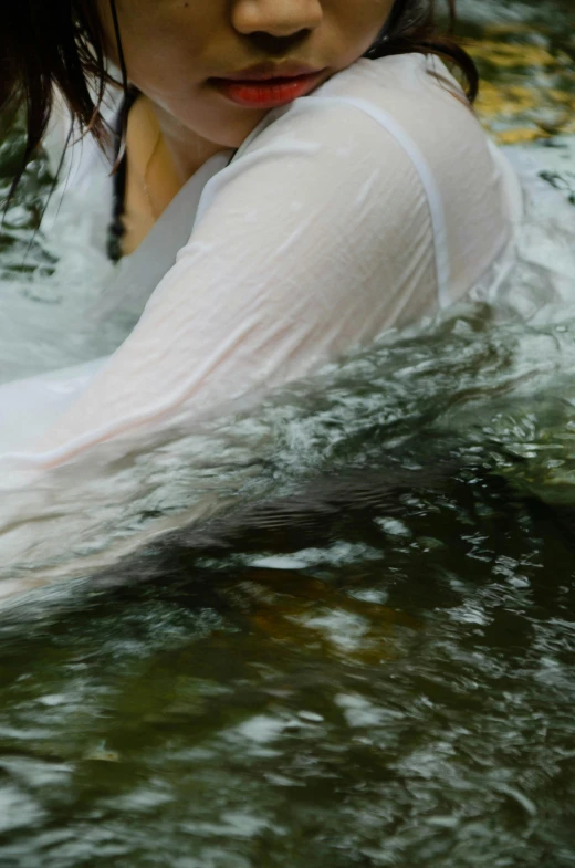 a woman sitting in a body of water with her hands on the side of her head