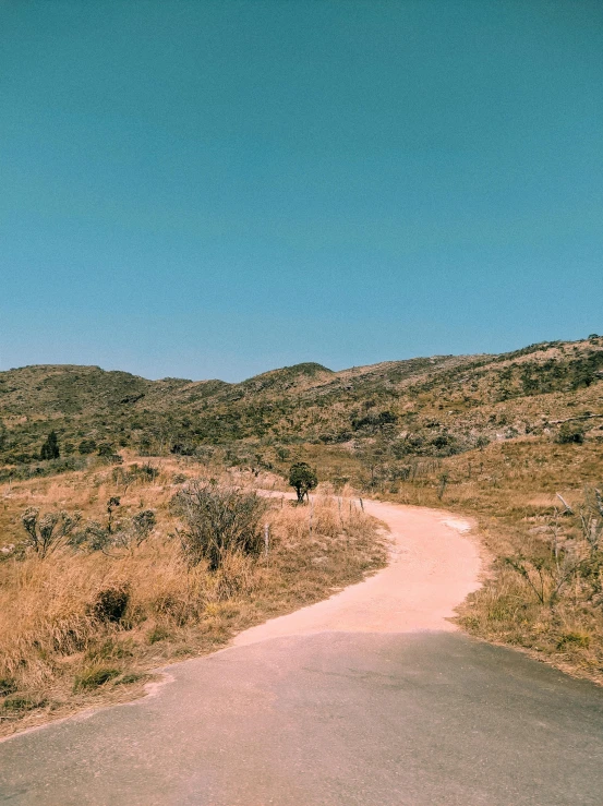 the person walks along the dirt road near the hill