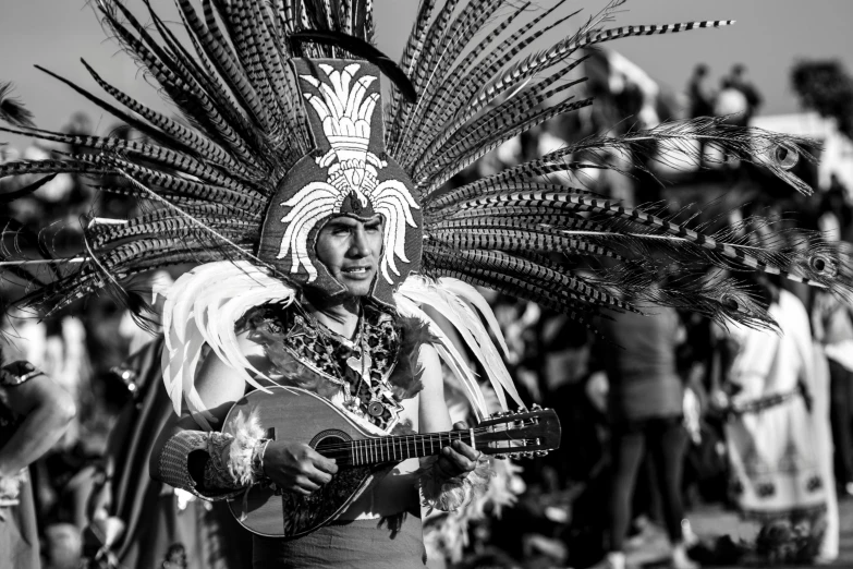 the man is wearing a headdress with feathers and holding a guitar