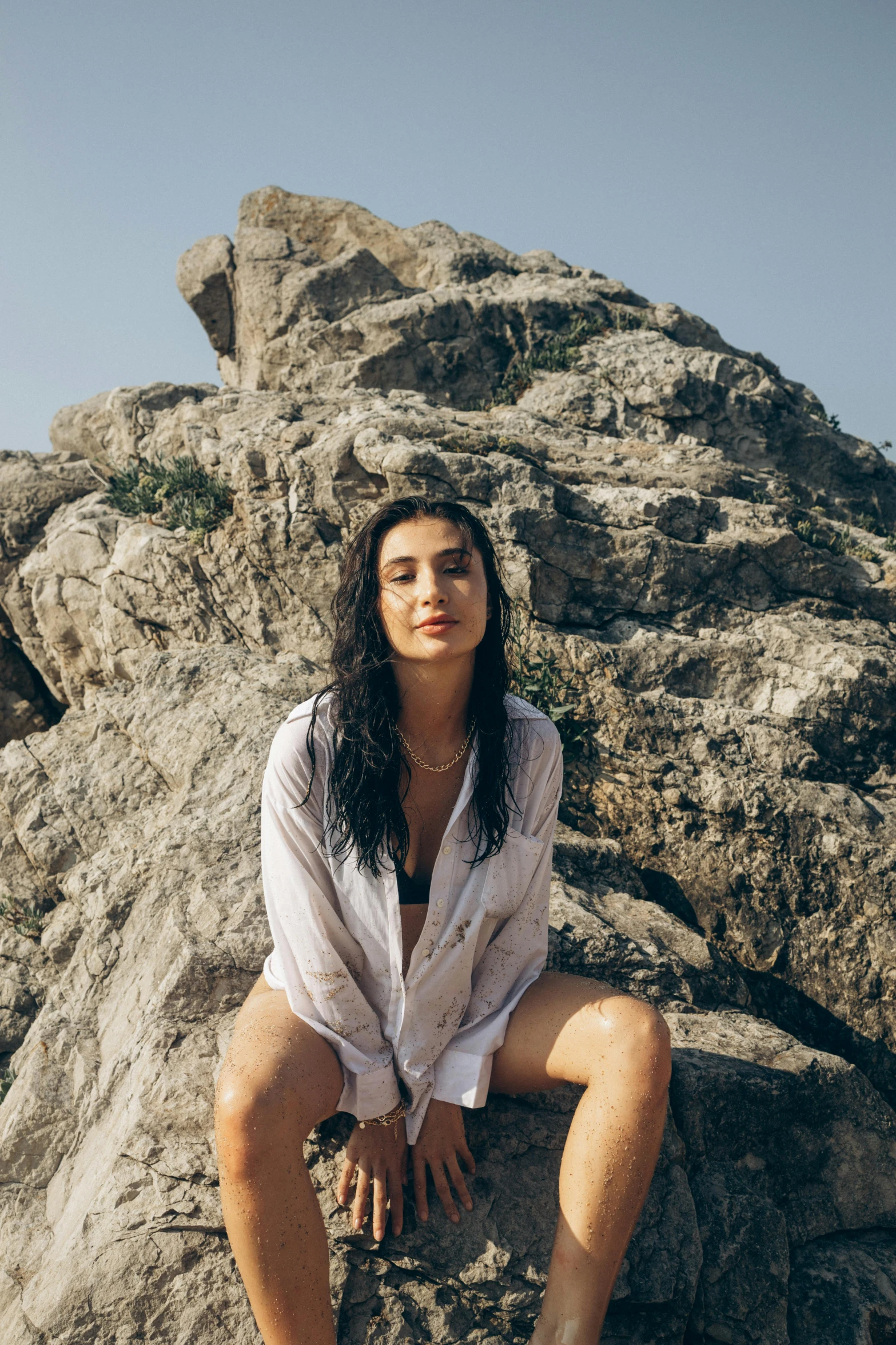 woman sitting on large rock with desert scene in background